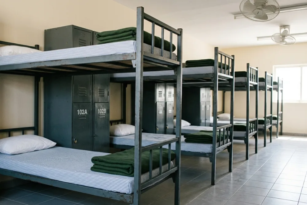 Sturdy double-decker metal bunk beds with personal lockers in a basic UAE labor camp sleeping area
